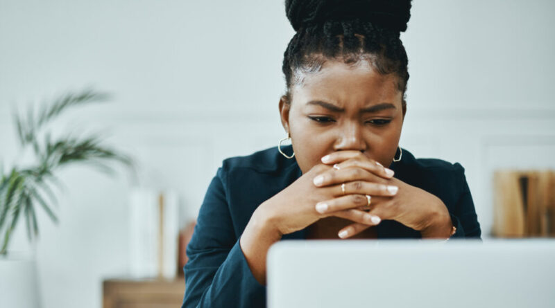 Shot of a young businesswoman frowning while using a laptop in a modern office