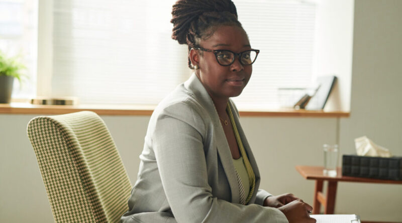 Portrait of African American psychologist in eyeglasses sitting on armchair